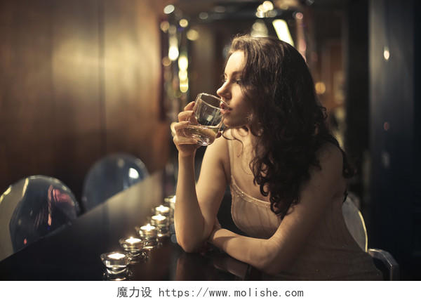 漂亮的女人在酒吧里喝的威士忌豪华高尚酒馆酒吧灯光吧台背景